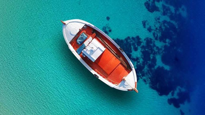 shutterstock_1287125749 Small boat floating over clear turquoise water