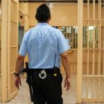 Fellow Inmates Make Celebrity’s BED — The Bed Is The LEAST Of It corrections officer walking through prison corridor