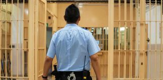 Fellow Inmates Make Celebrity’s BED — The Bed Is The LEAST Of It corrections officer walking through prison corridor