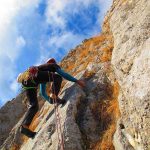 Helicopter Inches From Granite — Then This A climber ascending a rocky cliff under a blue sky