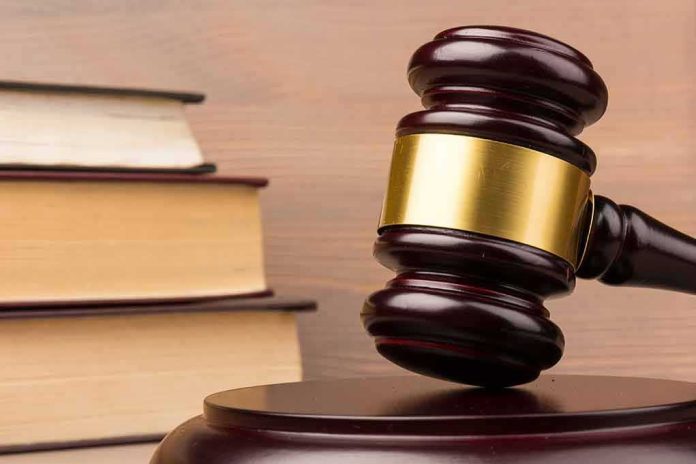 shutterstock_1662178945 Judge's gavel with gold band beside stacked law books