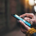 His Screen Said He Was Getting Rich — Until He Tried To Cash OUT Hands using a smartphone outdoors at night