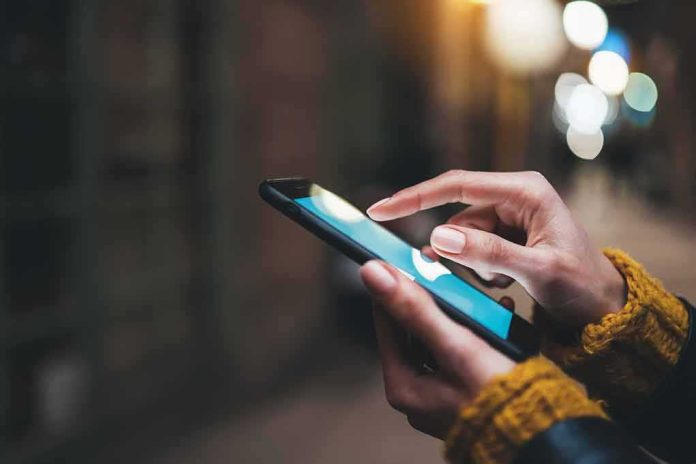 shutterstock_1674345967 Hands using a smartphone outdoors at night