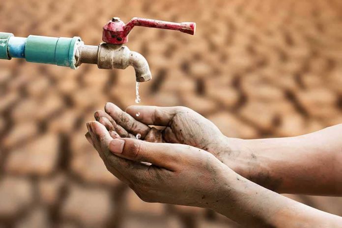 shutterstock_1680600826-1 Hands catching drops from a faucet over parched ground
