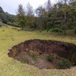She Was In Her Own Backyard — Then 8 Feet Of Ground OPENED Up Large sinkhole in a grassy field near a forest