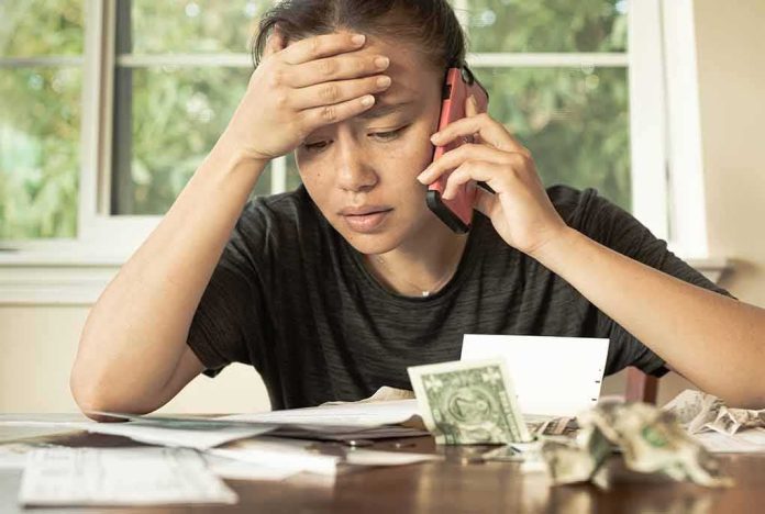 shutterstock_1725159478 Person on phone reviewing bills at a table