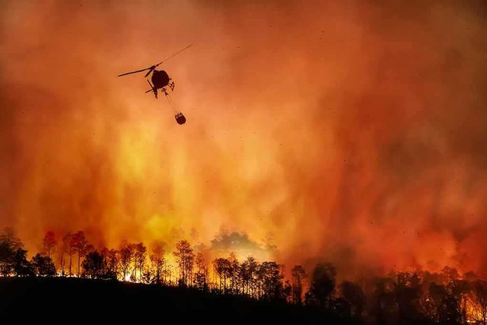 shutterstock_1810018291-1 Helicopter fights massive wildfire over burning forest