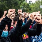 Protesters Stormed The Runway — Look Who Grabbed THEM Crowd of protesters with raised fists wearing masks