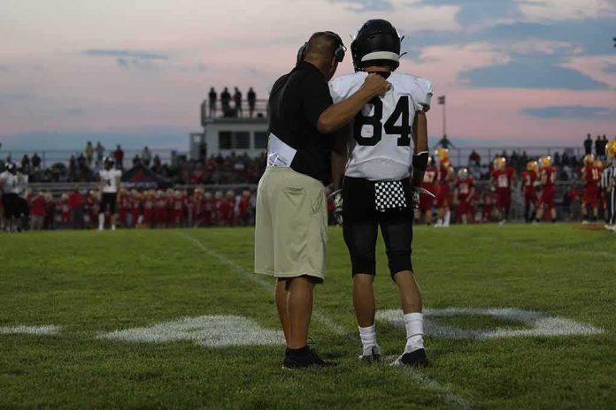 football coach with arm around player number 84 on sideline