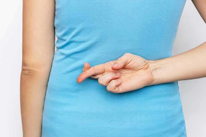 shutterstock_2089313188 Person with crossed fingers behind their back
