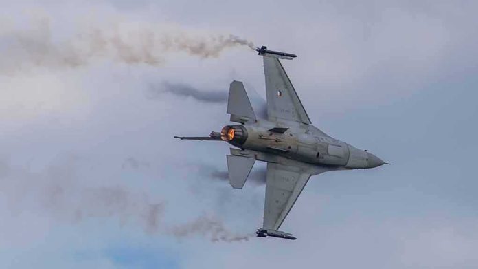 shutterstock_2143879765-1 Fighter jet banking with afterburner against a cloudy sky