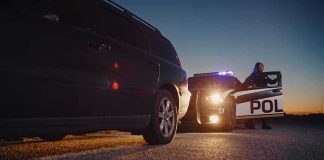 Trooper Dad Of Three Stopped The WRONG Car On I-65 Police officer at patrol car during traffic stop at dusk