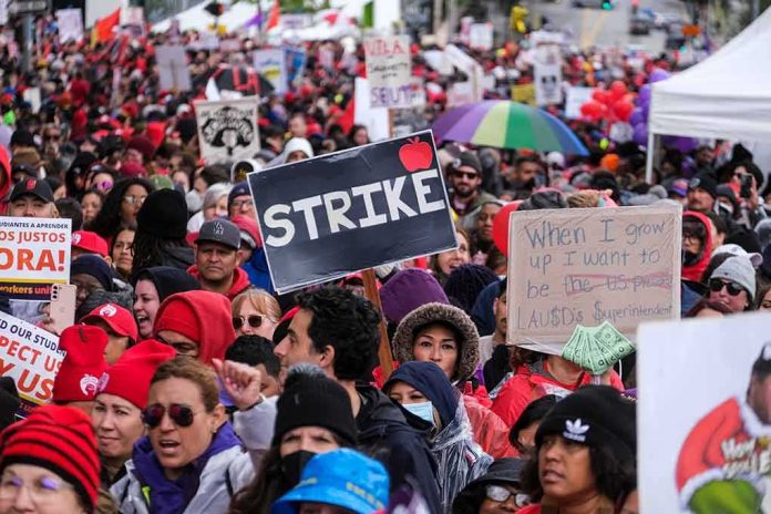 shutterstock_2278345523 Chuck Howley and Christian Jones in a large protest crowd holding strike signs