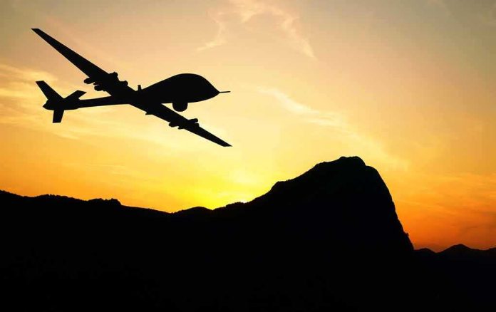 Drone silhouette flying over mountains at sunset
