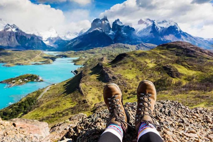 shutterstock_609626255-2 Hiking boots overlooking turquoise lake and jagged mountains