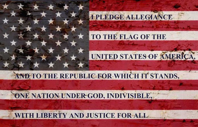 shutterstock_667528990 American flag with pledge text on a weathered surface