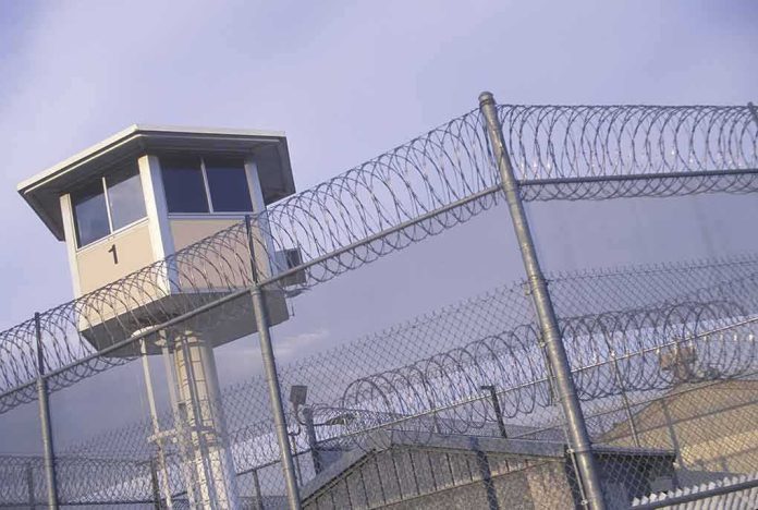 shutterstock_104591603 Prison watchtower behind barbed wire fencing