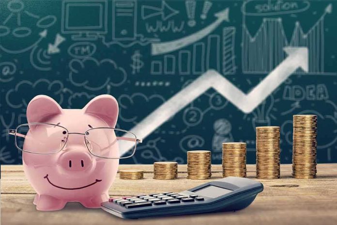 shutterstock_1156973119 Pink piggy bank with glasses beside stacked coins and a calculator