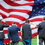 Feds Kept SHIELDING Illegal Immigrant — Then He STRUCK Veterans salute a large American flag