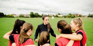 RECALL: 122,000 Cases Of Sports Drink — Is Your KID Drinking It? Coach talks to youth team in a huddle on a field