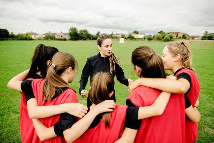 Coach talks to youth team in a huddle on a field