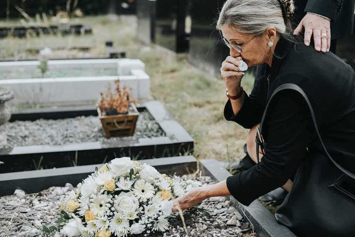 Woman placing flowers at a grave in a cemetery