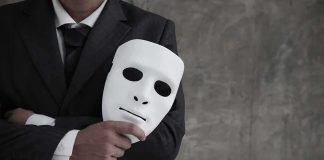 Husband Indicted After BIZARRE Overseas Ruse man in suit holding a white mask