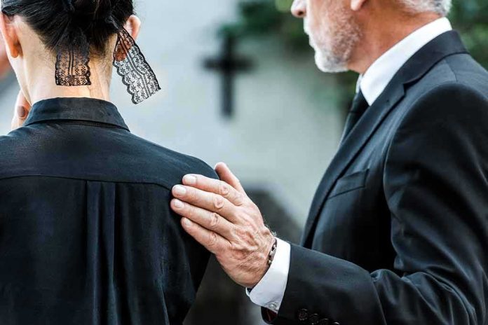 shutterstock_1500621305 Man in suit comforting a woman in black at a funeral