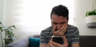 Dad Called And Called — Someone Made Sure NOBODY Came Man sitting on couch looking worried at smartphone