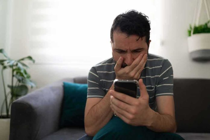 Man sitting on couch looking worried at smartphone
