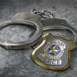 Cop Accused Of Grooming A Girl — Look Where He MET Her Handcuffs and police badge on a gray surface