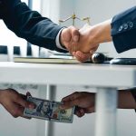Deputies SOLD Their Badges — And One Did Far WORSE businesspeople handshake with hidden cash exchange under table