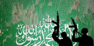 Chilling Note Found In Terrorist’s Sock silhouettes of armed figures in front of a weathered green wall with white script