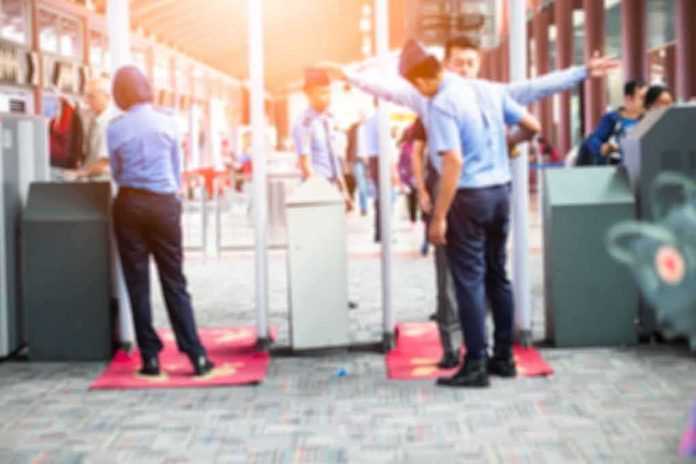 Security officers screen people at walk-through metal detectors