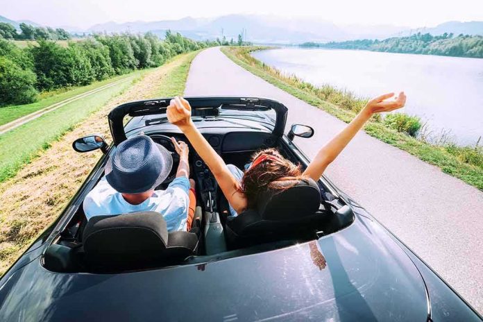 Couple in a convertible driving along a lakeside road